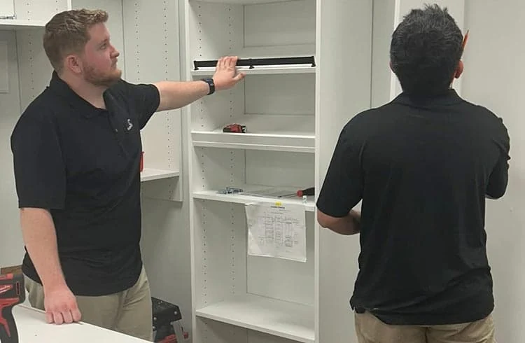 Two installers measuring and assembling custom cabinetry