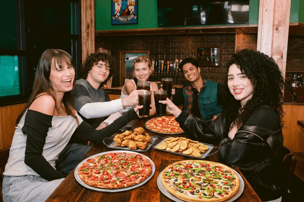 Friends sharing pizza, chicken and Mojo potatoes at a Shakey’s restaurant
